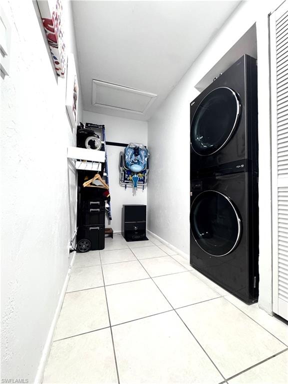 Laundry area with stacked washer and dryer and light tile patterned floors