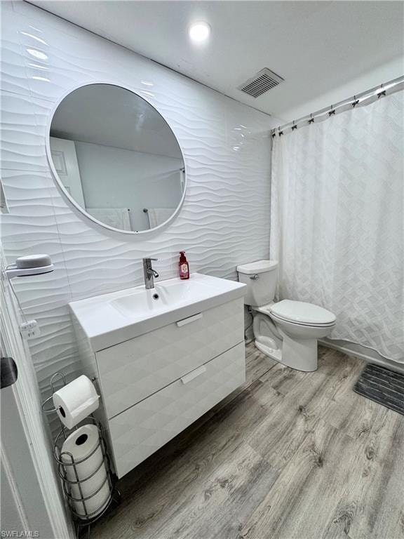 Bathroom with tile walls, vanity, wood finished floors, and a shower with shower curtain