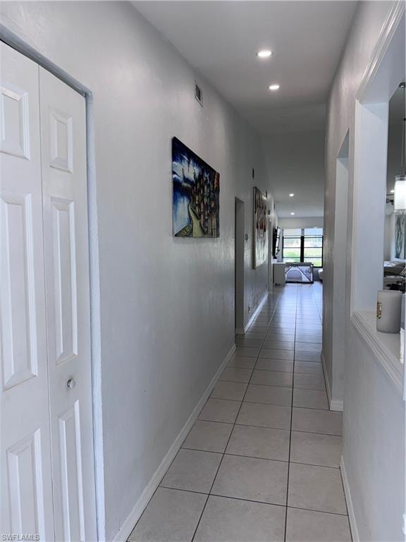Hall with light tile patterned floors and recessed lighting