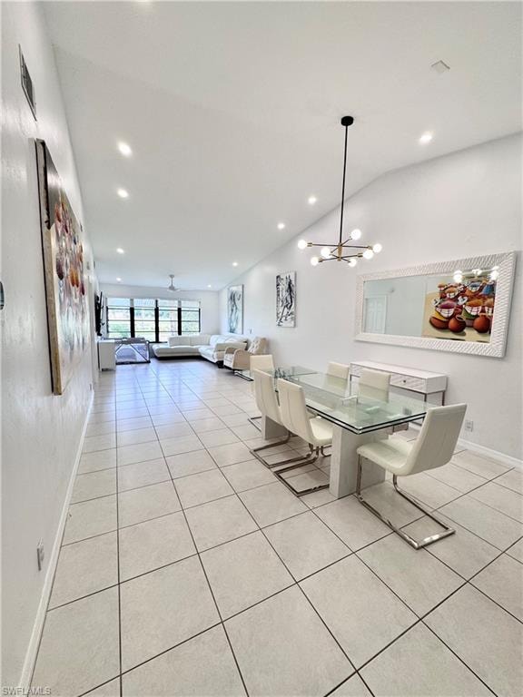 Dining area with light tile patterned floors, a chandelier, and lofted ceiling