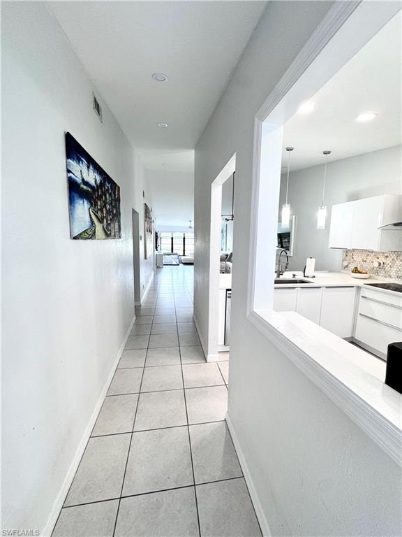 Hallway featuring light tile patterned floors and baseboards