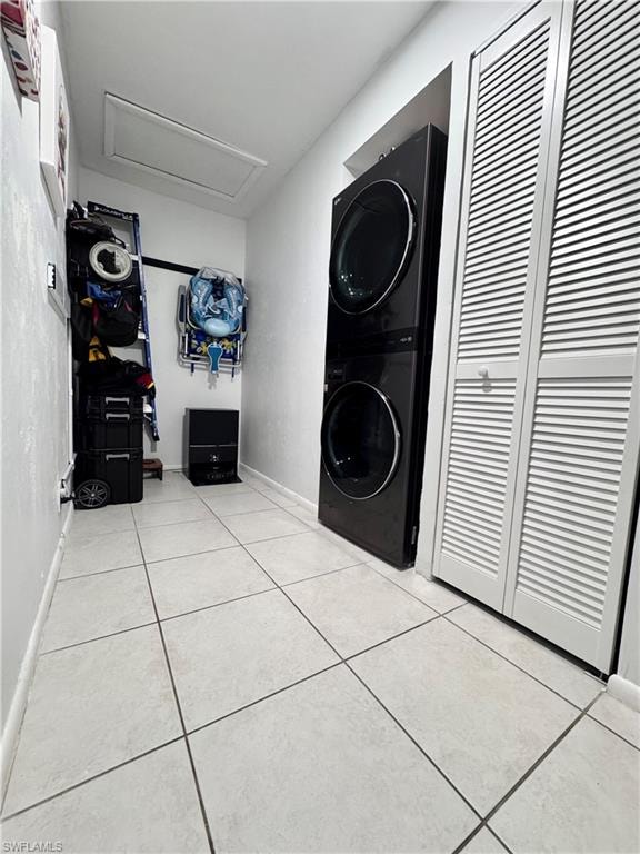 Laundry area with stacked washer / drying machine and light tile patterned flooring