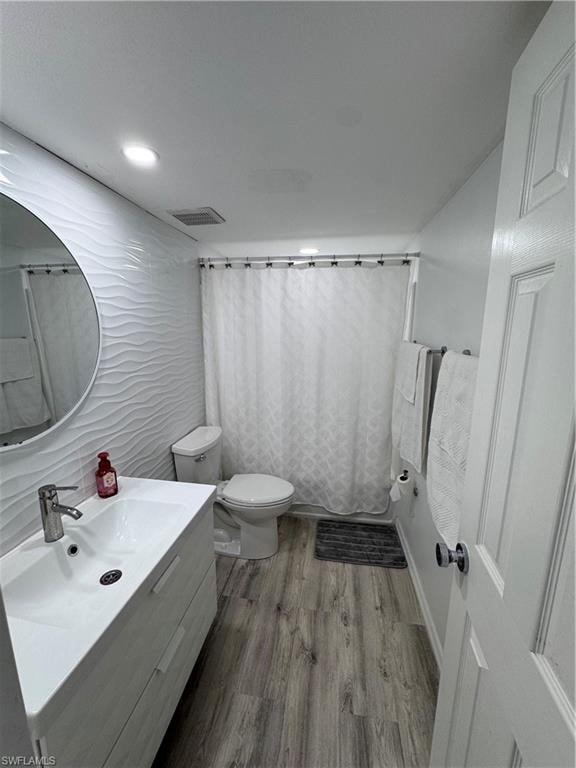 Bathroom with vanity, light wood finished floors, tile walls, and recessed lighting
