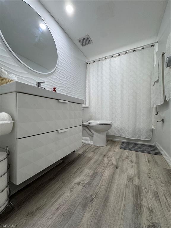 Full bath featuring light wood-style floors, shower / bath combo with shower curtain, and vanity