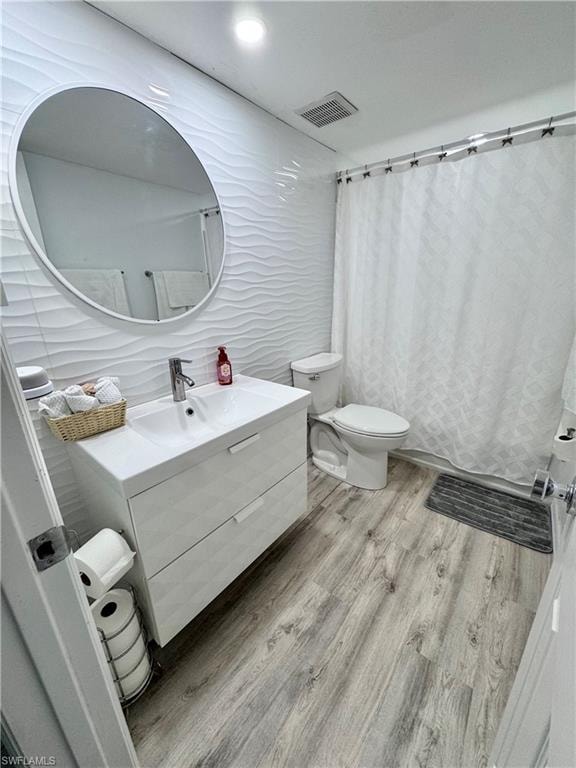 Bathroom featuring vanity, light wood-style flooring, a shower with shower curtain, tile walls, and recessed lighting