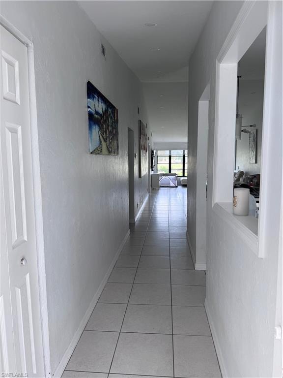 Hallway with light tile patterned floors and a textured wall