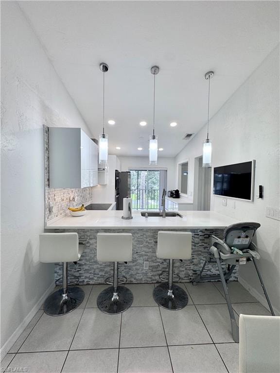 Kitchen featuring a breakfast bar, a peninsula, pendant lighting, and a textured wall