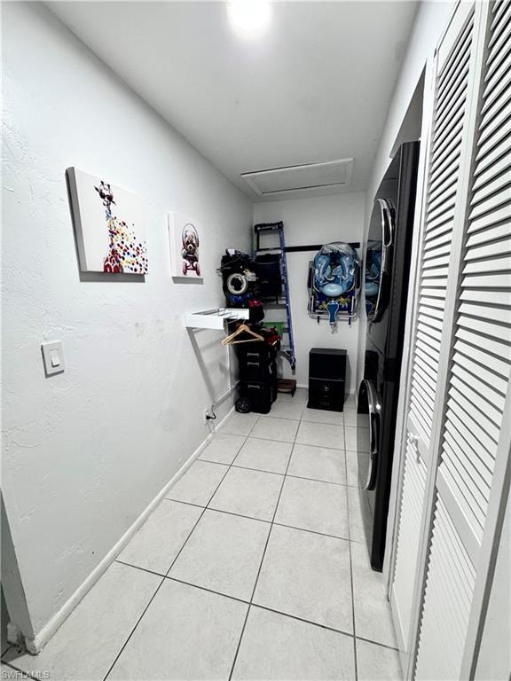 Laundry area featuring stacked washer and clothes dryer and light tile patterned flooring