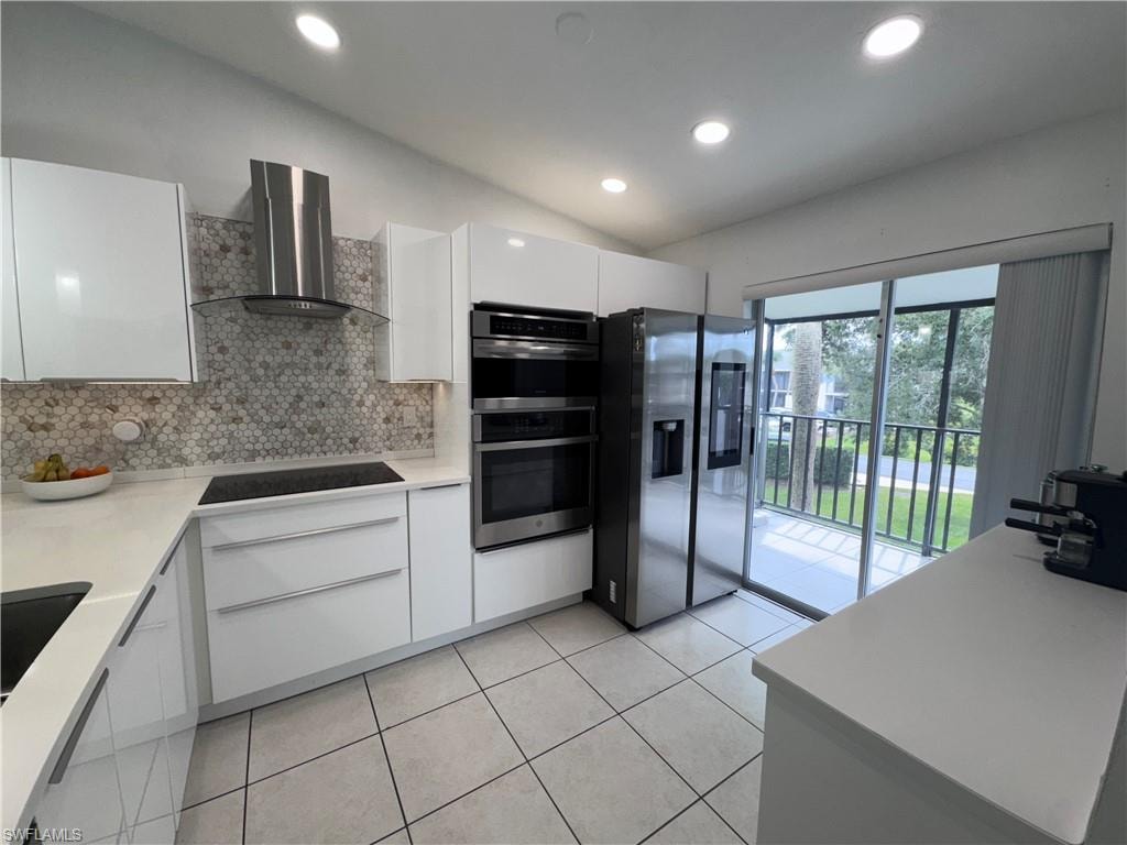 Kitchen with white cabinets, modern cabinets, stainless steel appliances, vaulted ceiling, and recessed lighting