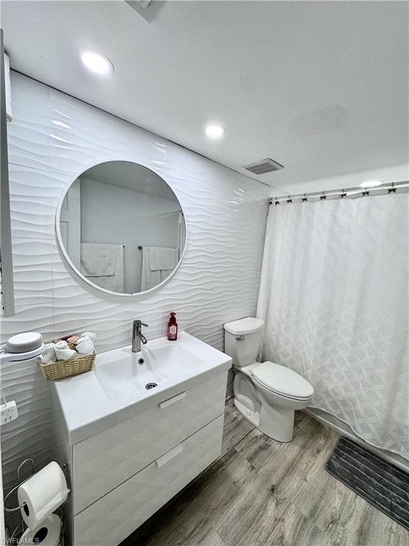 Bathroom with curtained shower, vanity, tile walls, wood finished floors, and recessed lighting