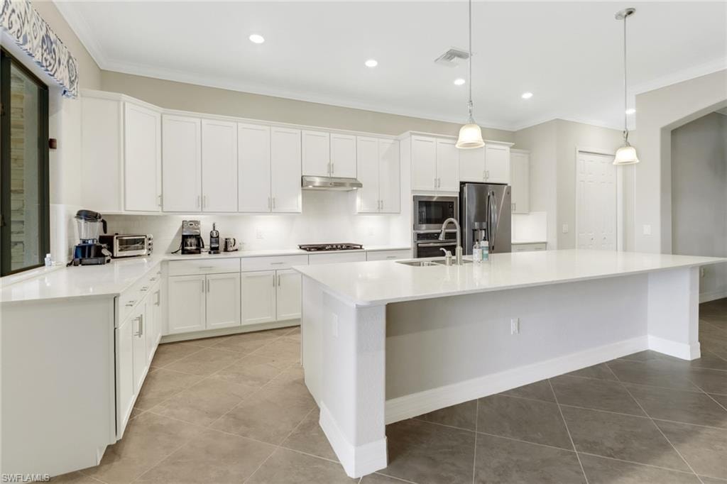 Light & bright kitchen with recessed & pendant lighting, a large island and stainless steel appliances