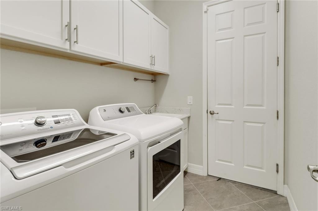 Laundry area with tile floors, cabinetry, laundry tub, washer and dryer