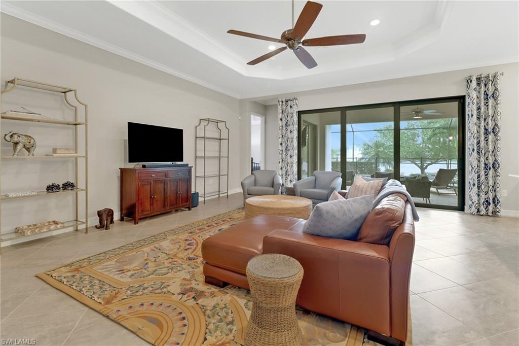 Tiled great room featuring tray ceiling, ceiling fan, and sliding glass door leading to the lanai