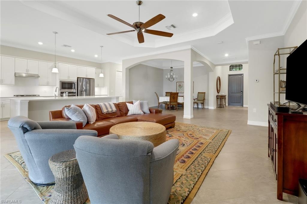 Light & bright great room with tile flooring, tray ceiling, and ceiling fan