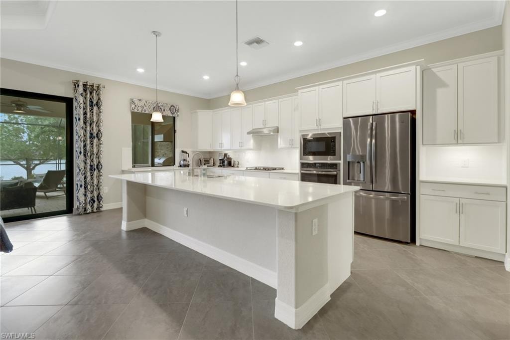 Light & bright kitchen with recessed & pendant lighting, a large island and stainless steel appliances