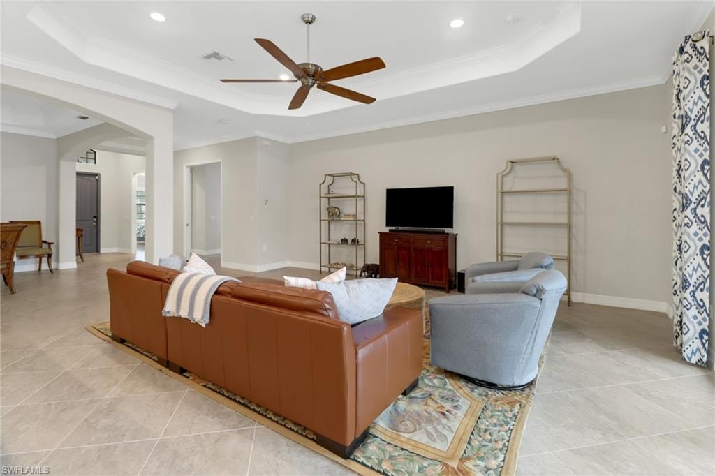 Light & bright tiled great room featuring tray ceiling and ceiling fan