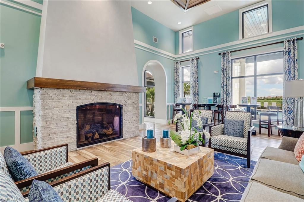 Amenity center gathering room featuring ample seating a stone fireplace