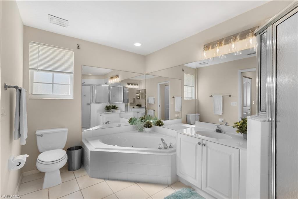 Full bathroom featuring toilet, a stall shower, plenty of natural light, a tub with jets, and tile patterned flooring
