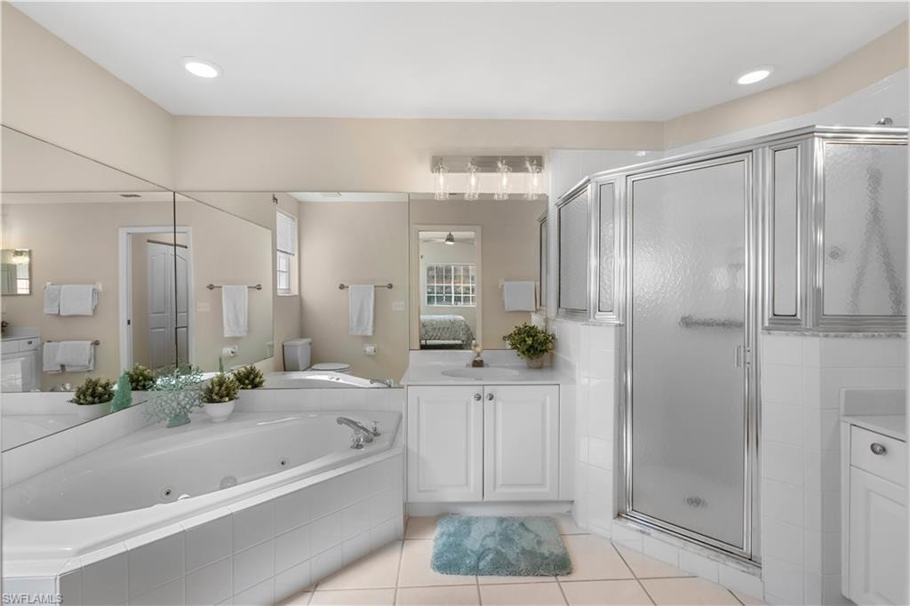 Full bathroom with a stall shower, connected bathroom, a tub with jets, tile patterned flooring, and vanity