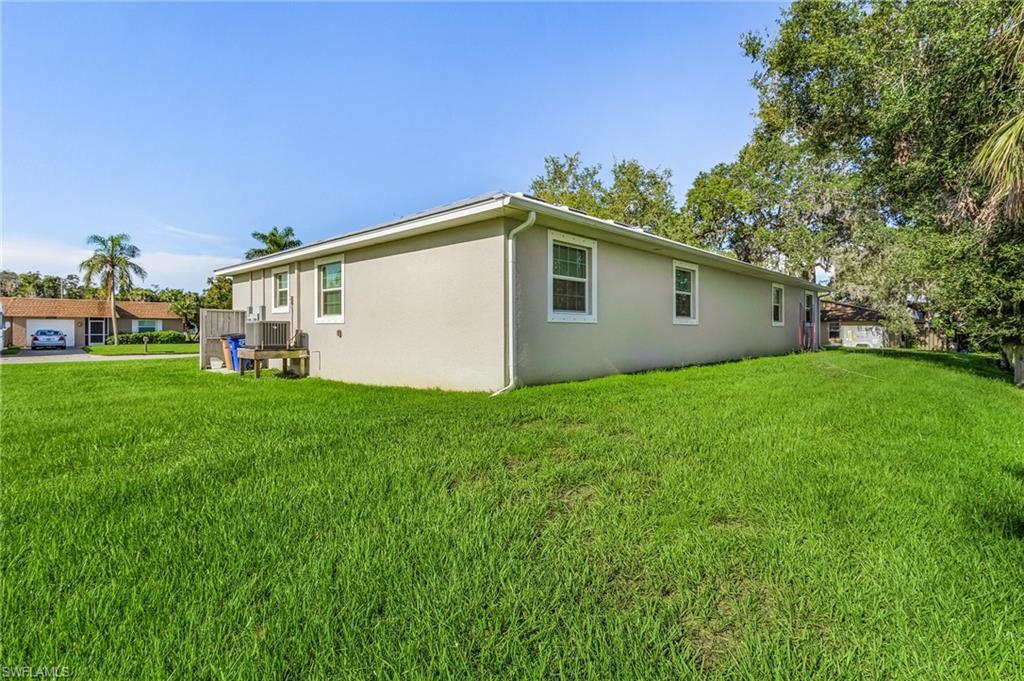 View of side of property featuring a lawn and stucco siding