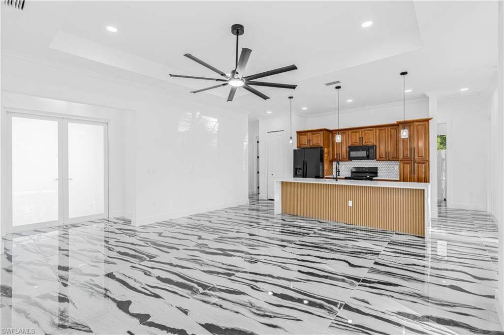 Unfurnished living room featuring recessed lighting, a ceiling fan, a tray ceiling, and light marble finish flooring