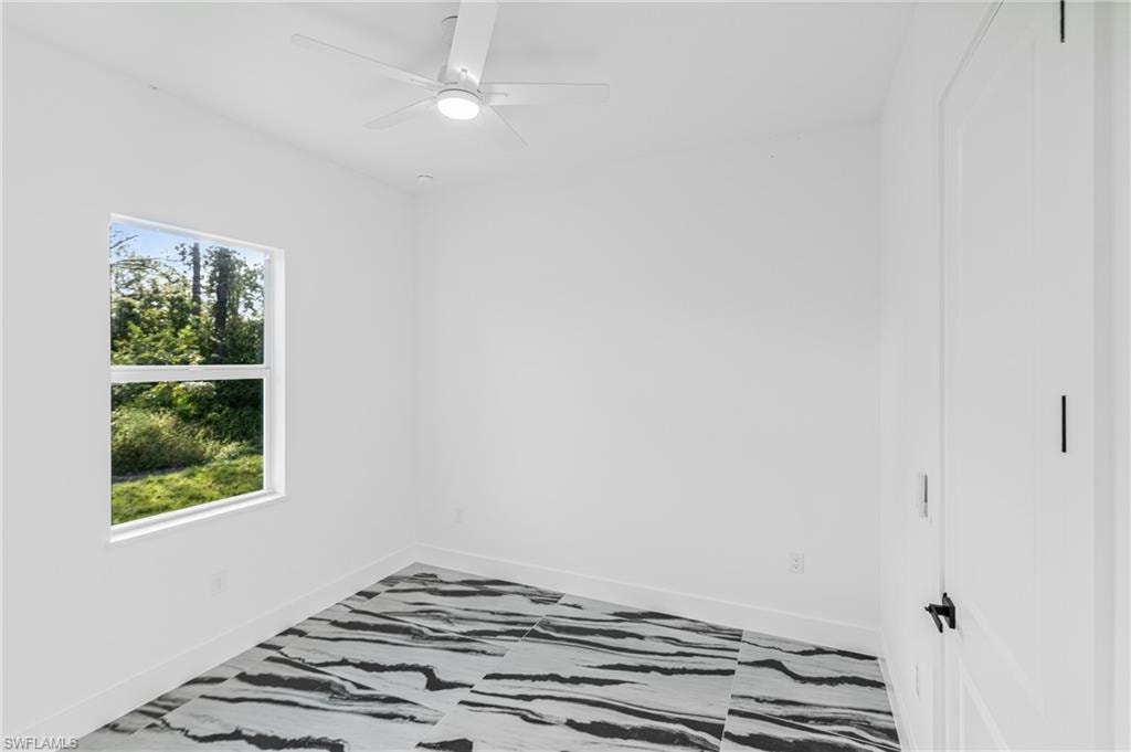 Spare room featuring a ceiling fan and baseboards