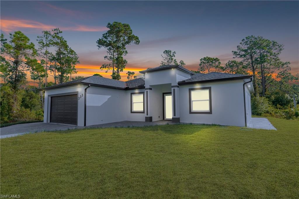 Prairie-style house featuring a lawn, concrete driveway, a garage, and stucco siding