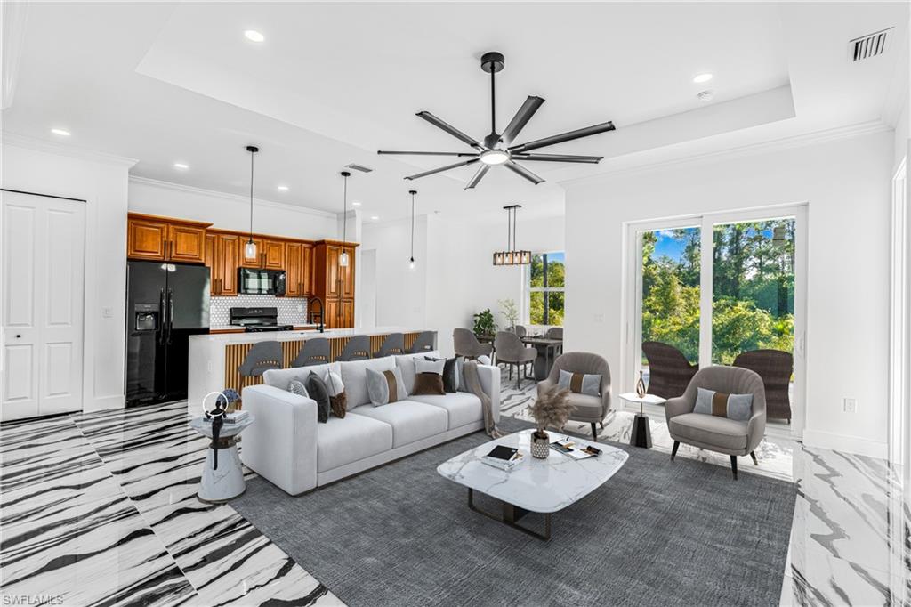 Living room with ornamental molding, a ceiling fan, recessed lighting, and a tray ceiling