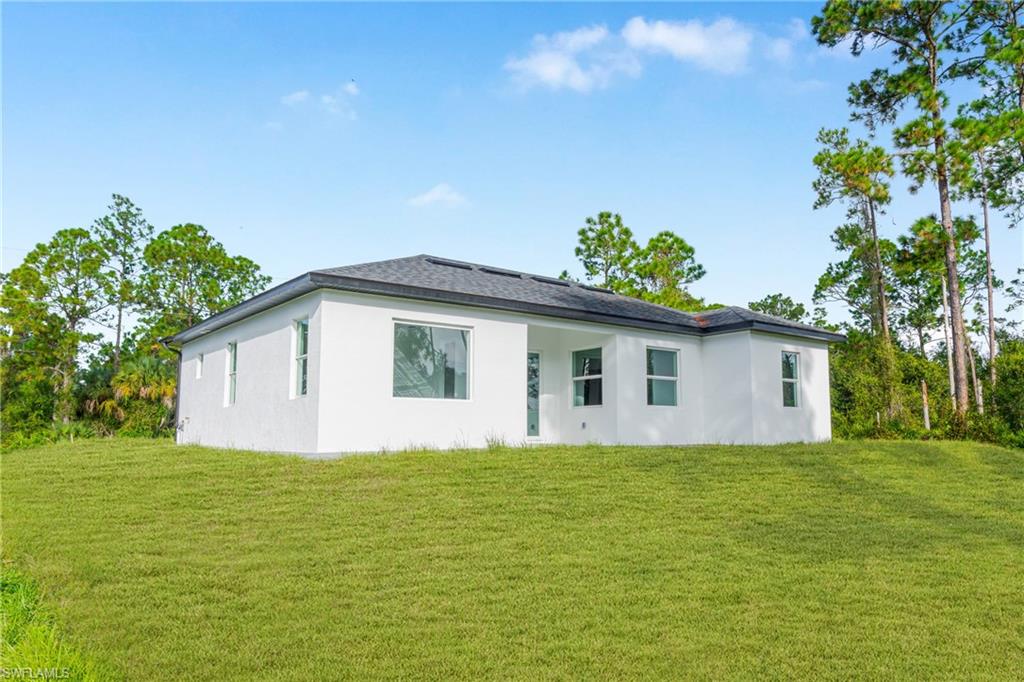 Rear view of house with stucco siding and a yard