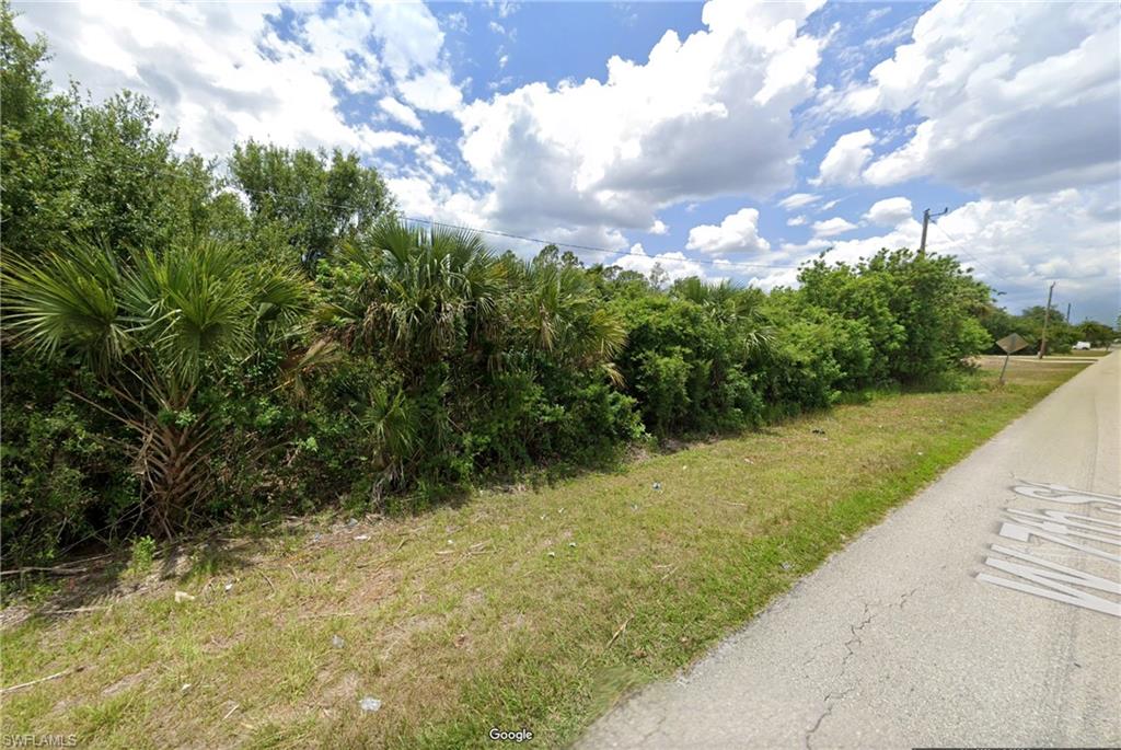 View of asphalt street featuring view of wooded area