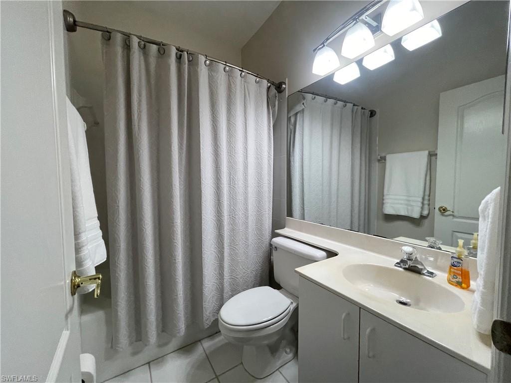 Bathroom featuring light tile patterned flooring, vanity, and shower / bath combo with shower curtain