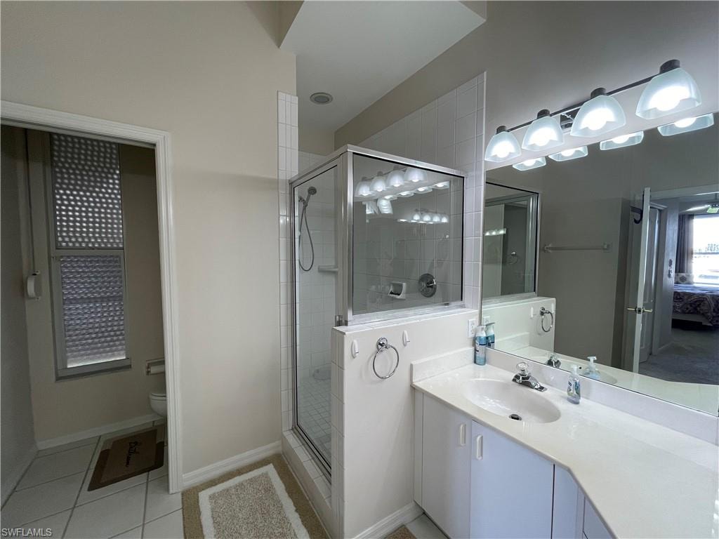 Bathroom with light tile patterned floors, a shower stall, vanity, and ensuite bath