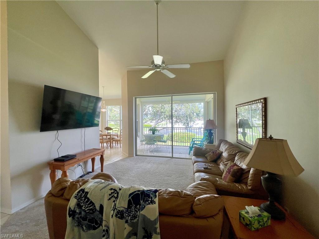 Living area featuring high vaulted ceiling, light carpet, and a ceiling fan