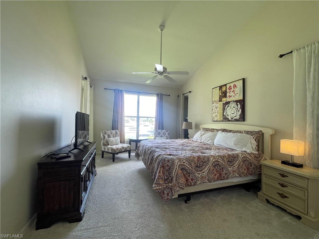 Bedroom with vaulted ceiling, light colored carpet, and ceiling fan