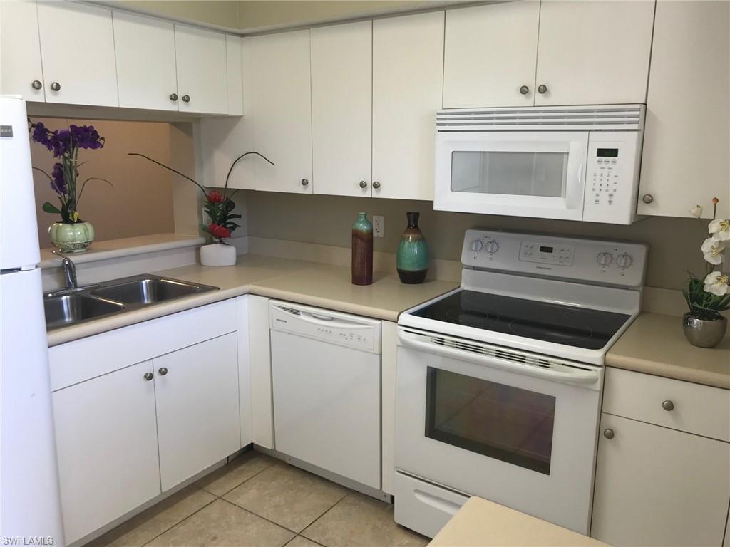 Kitchen featuring white appliances, light countertops, white cabinetry, and light tile patterned floors