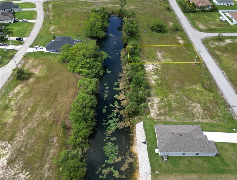 Aerial view of residential area with a large body of water and property boundaries highlighted