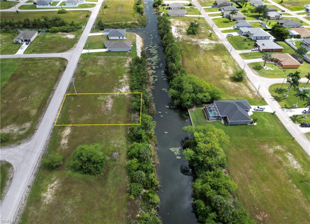 Aerial view of residential area with a large body of water and property parcel outlined