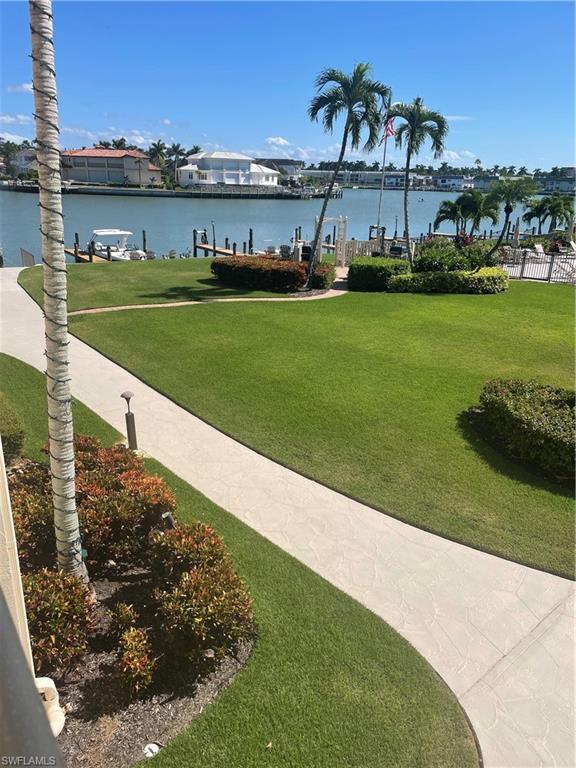 Surrounding community with a yard, a water view, and a dock
