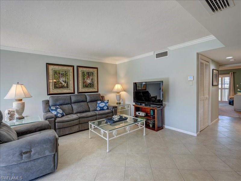 Tiled living room featuring ornamental molding and baseboards
