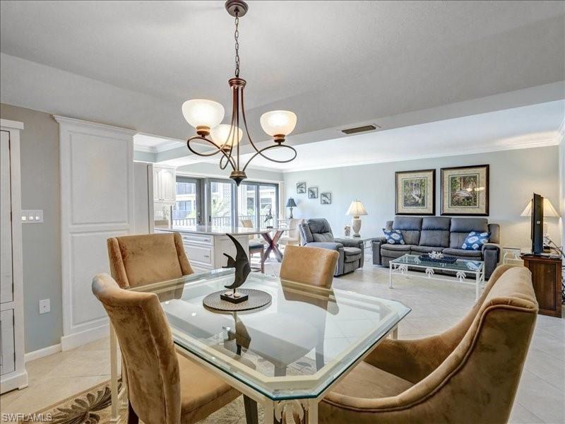 Dining space featuring light tile patterned flooring, a chandelier, and crown molding
