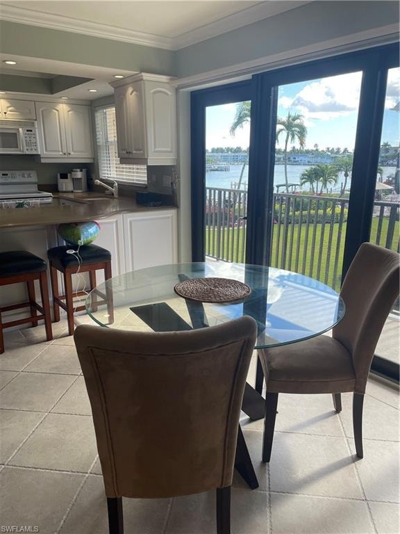 Dining room featuring ornamental molding, a water view, and light tile patterned floors