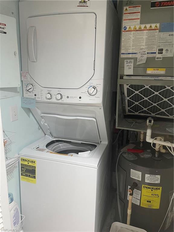 Laundry area featuring water heater, stackedwasher / dryer, and heating unit