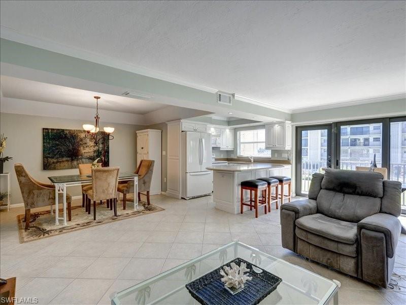 Living room featuring light tile patterned floors, a chandelier, and crown molding