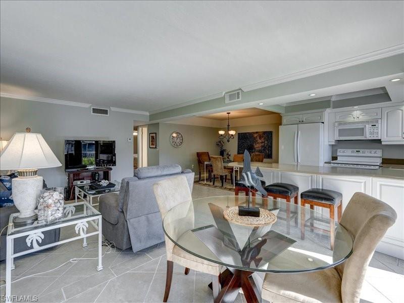 Dining space with crown molding, a chandelier, light tile patterned flooring, and recessed lighting