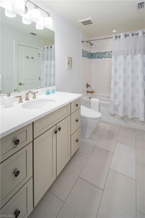 Full bathroom featuring shower / tub combo with curtain, light tile patterned floors, and vanity