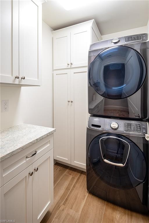 Laundry area with cabinet space, light wood finished floors, and estacked washer and dryer