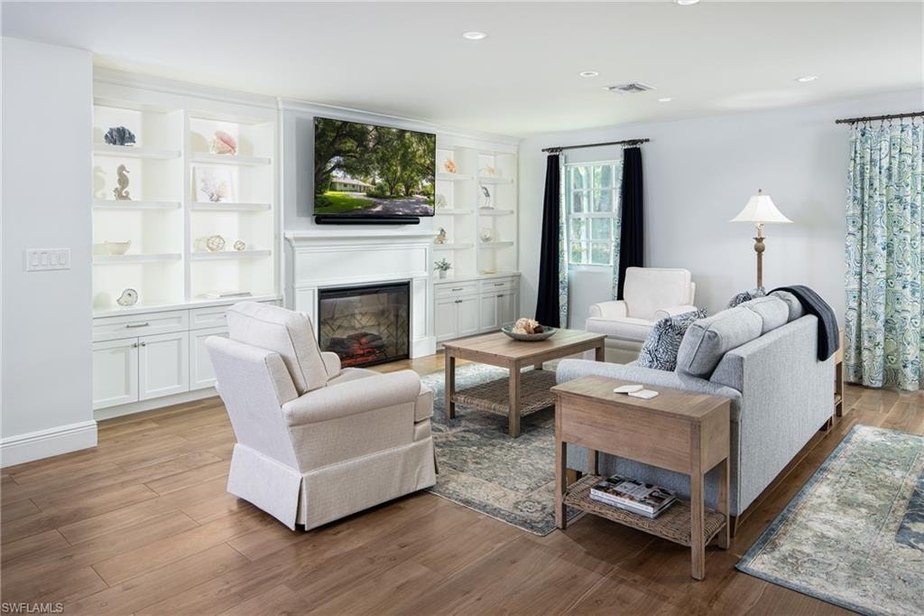 Living area featuring a glass covered fireplace, light wood-style floors, and recessed lighting