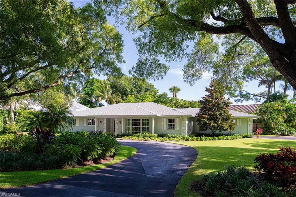 Ranch-style home with curved driveway and a front lawn