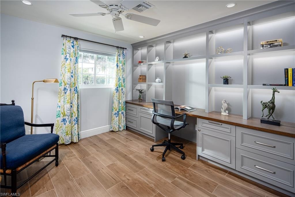 Office featuring built in desk, light wood finished floors, recessed lighting, and ceiling fan