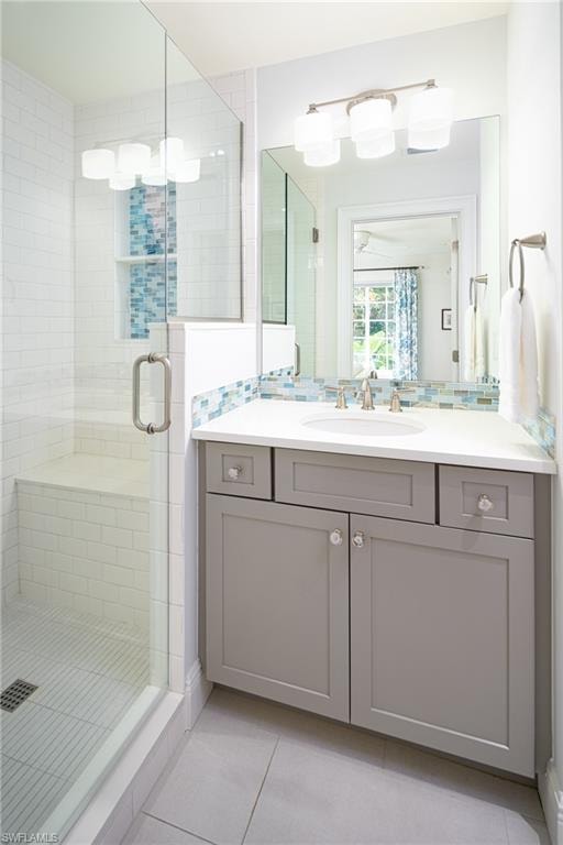Full bath featuring light tile patterned flooring, a shower stall, vanity, and tasteful backsplash